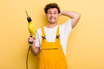 young handsome guy feeling stressed, anxious or scared, with hands on head. handyman with a drill...