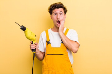 Fototapeta young handsome guy feeling shocked and scared. handyman with a drill concept obraz