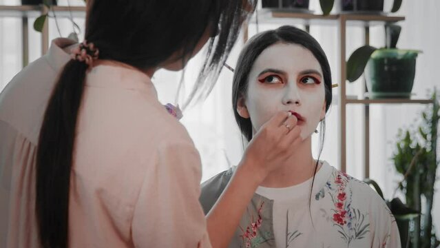 A young woman creates the image of a geisha for a girl. Makeup. Creating an image for an event