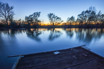 Sunset over the fishing pier at the backwater in Hungary. Long exposure shot.