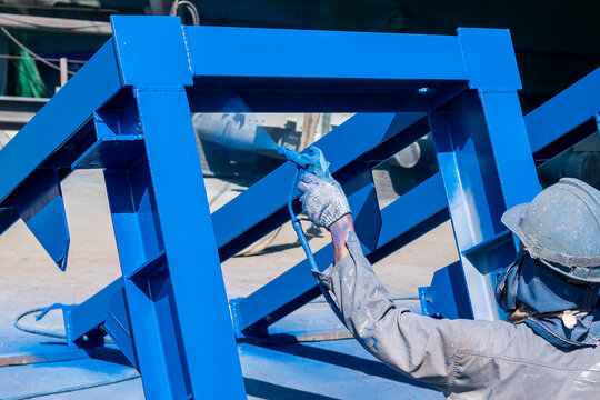 After complete fabrication at an industrial factory, the painter uses a spray gun to paint a steel structure.