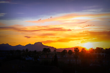 Denia Spain sunset with palm trees bright colourful sky and view to mountains