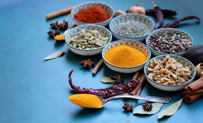 Close up photo of spices and herbs in blue ceramic bowls. Paprika, turmeric, anise, lavender,...