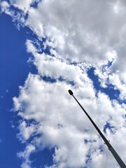 Street lamp post against blue sky with beautiful white clouds.  Peaceful background with copy space. 