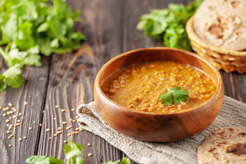Indian dal food (Masoor Dal or Dal Tadka Curry) and homemade Flatbread Chapati. Traditional Indian soup lentils. Indian Dhal spicy curry in bowl, spices, herbs, rustic black wooden background. - obrazy, fototapety, plakaty