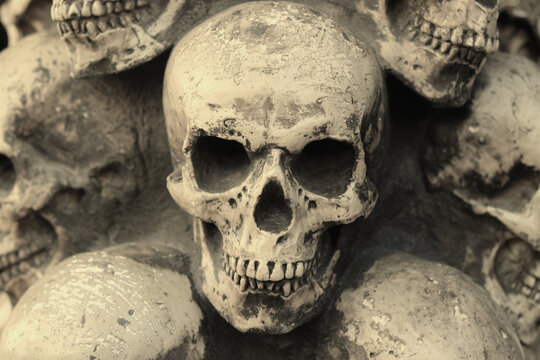 Close-up black and white photo of skulls against background of other skulls as reminder of death in form of skull or fear of death with skull