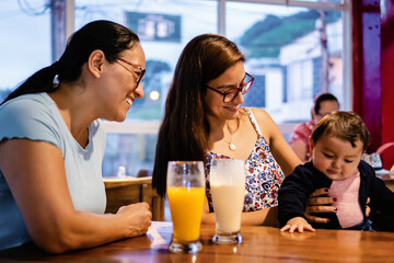 mother and baby daughter with grandmother latinas in a restaurant, family reunion