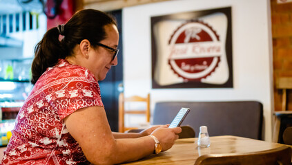 middle-aged latina woman ordering in a restaurant by mobile phone