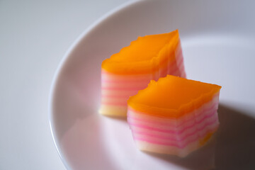 Nyonya delights dessert “Kuih Lapis” (Steamed Layer cake desserts) on white plate and isolated...