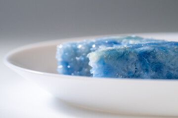 Nyonya delights dessert “Kaya Kuih” (Blue Glutinous Rice Cakes) on white plate and isolated white background.