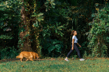 casual woman walk with her golden retriever dog through the park in a morning