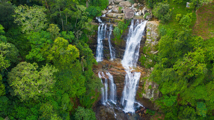 A tropical waterfall in a mountain canyon surrounded by jungle. Lower Ramboda Falls. Sri Lanka.