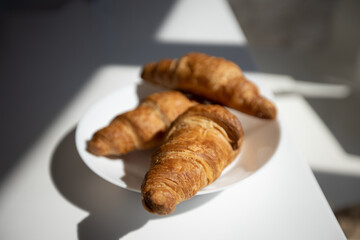 three appetizing rich fresh croissants on a white plate