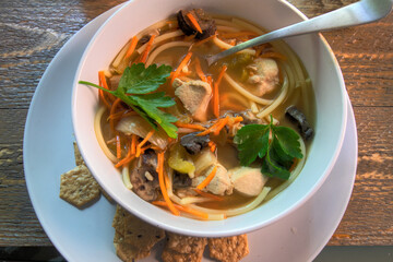 Top View Of Chicken Noodle Soup on natural wood surface.