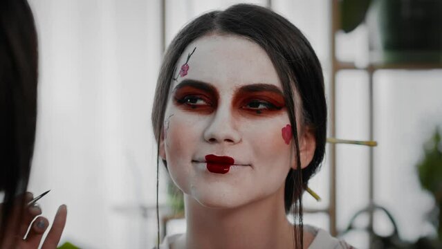 Close-up A young woman creates the image of a geisha for a girl. Makeup. Creating an image for an event