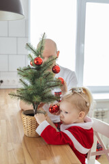Obraz na płótnie Canvas Father with toddler daughter with cochlear implants having fun in christmas living room - inclusion and innovating treatment for deafness with cochlear implant surgery