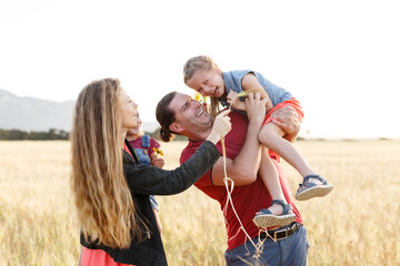 Happy family father of mother and two daughters sisters on nature at sunset.Carefree parents having fun with their kids on a field.