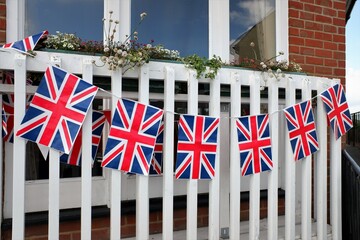 Row of Union Jack flags attached to wooden fence