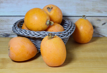Close up, group of medlars on a wooden board and a wicker basket. Healthy food. 