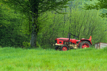 The old, veteran but reliable tractor standing on the field. Symbol for rural agriculture and machinery used there. 