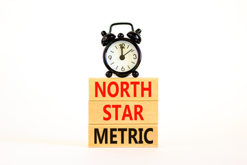North star metric symbol. Concept words North star metric on wooden blocks on a beautiful white table white background. Black alarm clock. Business, finacial and north star metric concept. Copy space.