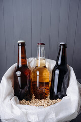bottles with craft beer in a bag of barley malt.  Ale or lager from pilsner malt.  homemade home-brewed beer. - obrazy, fototapety, plakaty