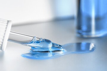 Pipette with fluid serum, oil, face gel cleaner. Cosmetics and healthcare concept closeup. Dose of retinol with air bubbles. Flat lay. Monkeypox, coronavirus research