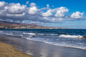 Sandy beach with black stones at Punta de Maspalomas, Gran Canaria, Spain