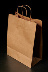 Top view of a brown paper bag with handles insulated on a black background. Layout for packaging....