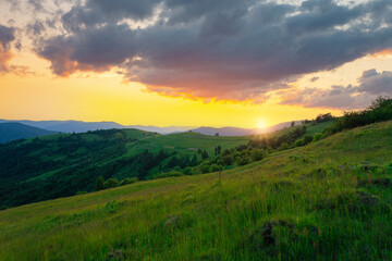 Naklejka na ściany i meble Stunning sunset sky with clouds over green hills. Summer countryside view. Carpathian mountains. Ukraine.