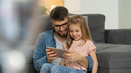Happy family, father and little child use digital tablet sitting at home. Computer games, surfing internet, social media, buy in online store