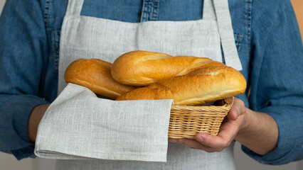 Close up of hands hold wicker basket with freshly baked bread. French baguette Bakery. Food