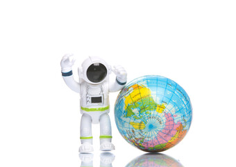 Toy astronaut with globe on white background with reflection