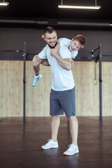 Healthy family concept. Father squats with his son on his shoulders in the gym. Fitness, sports,...