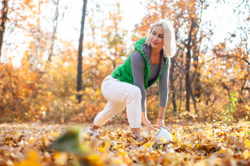 Beautiful active blonde woman training with medicine ball in autumn forest. Workout outdoor concept