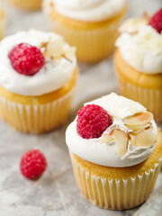 Macro shot. Festive muffins with cream, fresh raspberries, decorated with almonds on a white background. Food background. Birthday, holiday, romantic date. Advertising, banner.