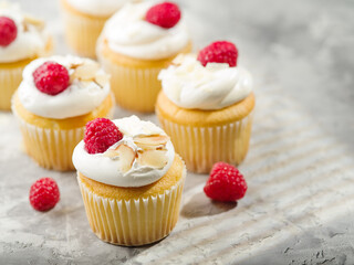 Many delicious muffins with whipped cream, fresh raspberries and almond slices on a white background. Festive composition. Birthday, banquet. Restaurant, hotel, cafe, deli, confectionery.