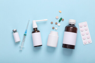 Mockaup of bottles medicines with white labels for branding, pills and syringe on blue background. Top view