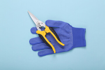 Garden pruner with work gloves on blue background. flat lay. top view