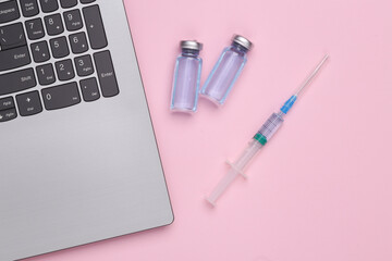 Laptop with a bottle of vacuina and a syringe on pink background. Top view