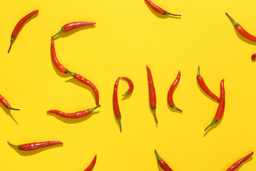 Word spicy made from red chili peppers on yellow background