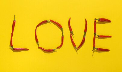 Word love made from red chili peppers on yellow background