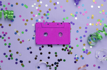 Audio cassette and colored streamer with confetti on purple background. Party,Music day