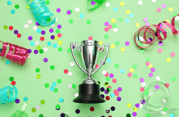 Winner cup and colored serpentine with confetti on green background. Winning the competition, awarding the winner