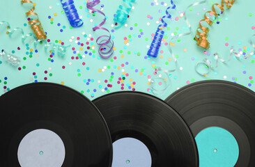 Vinyl records and colored streamer with confetti on blue background. Music day