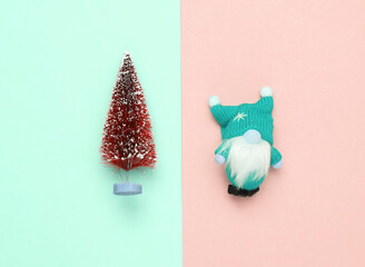 Christmas gnome and Christmas tree on pink blue pastel background. Top view