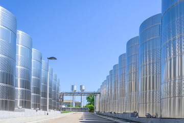 Fototapeta premium Wine steel tanks, equipment of contemporary winemaker factory. Barrels for wine storage. Equipment for the fermentation, distillation of alcohol. Preparation workshop for pure alcohols.
