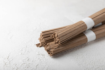 Buckwheat soba pasta on a white background.Raw noodles. Ingredients for a gluten free dish. Dried buckwheat soba noodles. Traditional Japanese food. Healthy food. Place to copy.