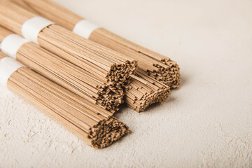 Buckwheat soba pasta on a white background.Raw noodles. Ingredients for a gluten free dish. Dried buckwheat soba noodles. Traditional Japanese food. Healthy food. Place to copy.