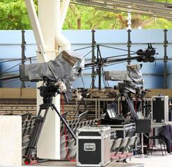 Two TV cameras on tripods. The cells are covered with covers. TV broadcasting equipment. Summer...